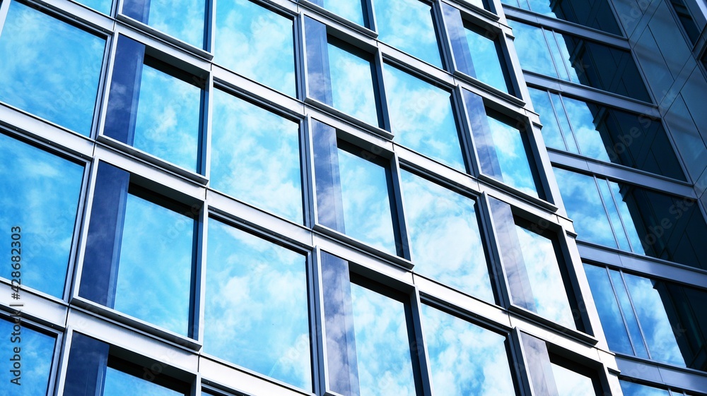 Abstract closeup of the glass-clad facade of a modern building covered in reflective plate glass. Architecture abstract background. Glass wall and facade detail. Velvia graphic filter. Abstract closeup of the glass-clad facade of a modern building covered in reflective plate glass. Architecture abstract background. Glass wall and facade detail. Velvia graphic filter.