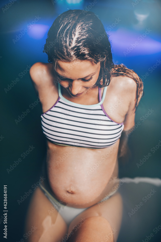 Obraz premium Beautiful pregnant woman floating in tank filled with dense salt water used in meditation, therapy, and alternative medicine.