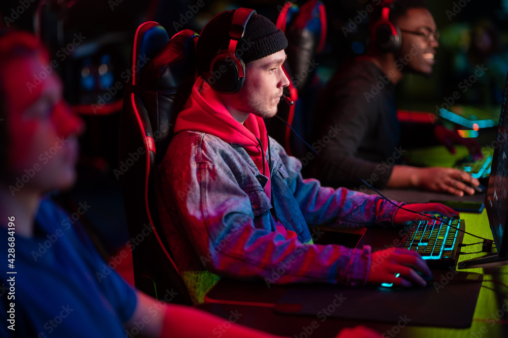 Training bootcamp for professional esports players. Young cyber-athletes play an online shooter game. Glowing keyboard, neon light. Training bootcamp for professional esports players. Young cyber-athletes play an online shooter game. Glowing keyboard, neon light.