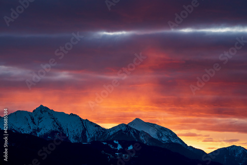 Rocky alpine mountain range during sunset with red illuminated clouds in Tirol, Austria