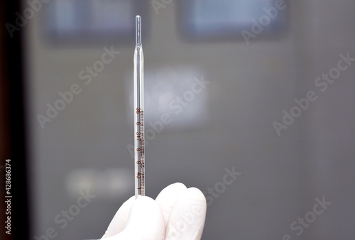 a medical personnel holding an oral mercury temperature measuring thermometer  photo