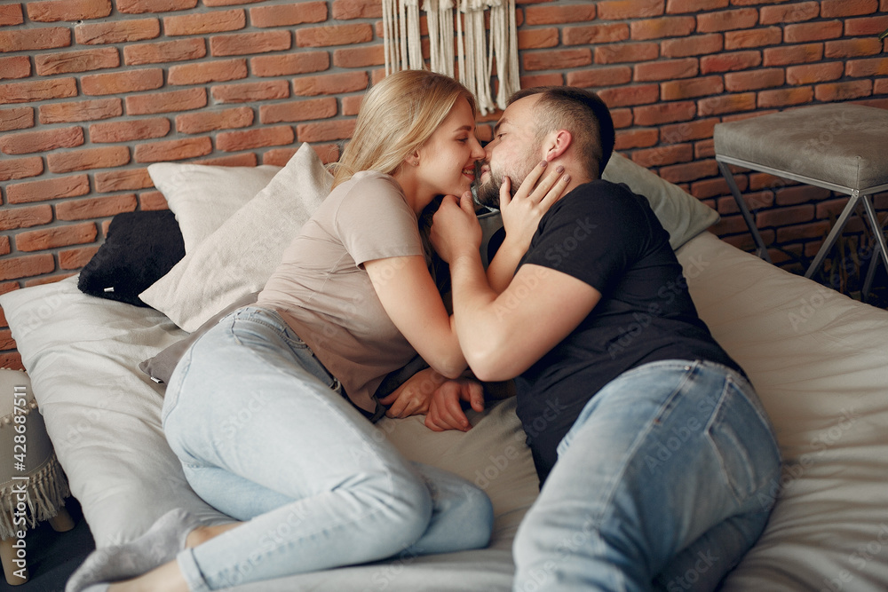 Couple sitting on a bed in a room Couple sitting on a bed in a room