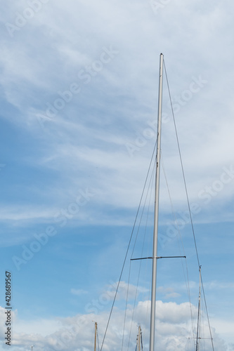 sailboat mast over blue sky with clouds