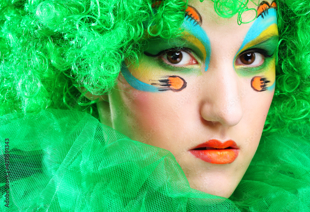 Pretty young woman in a green wig and with festive makeup. Holiday and party concept.
