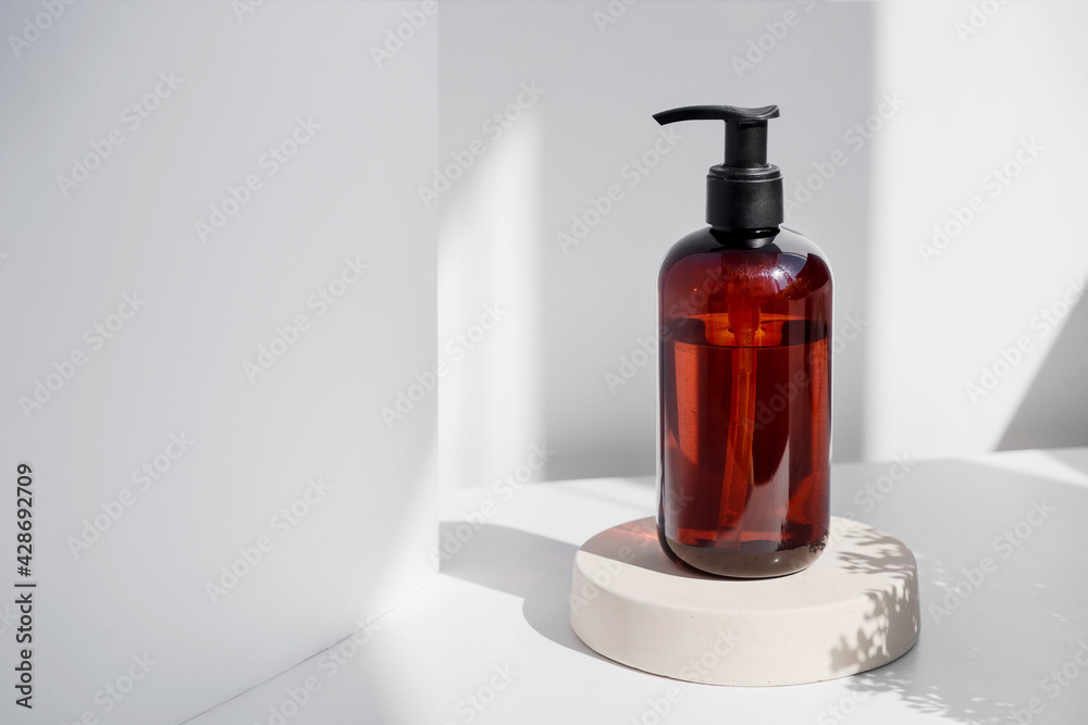 Brown glass bottle on white background in the morning rays of light. Eco cosmetic cream, serum for skin, face and body. Concept of skincare, spa and wellness center. Natural beauty products