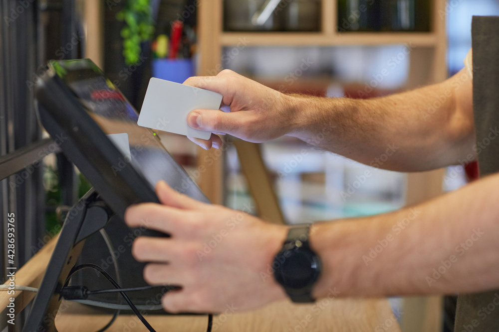 Close up of unrecognizable man using register in cafe while processing orders and payments, copy space