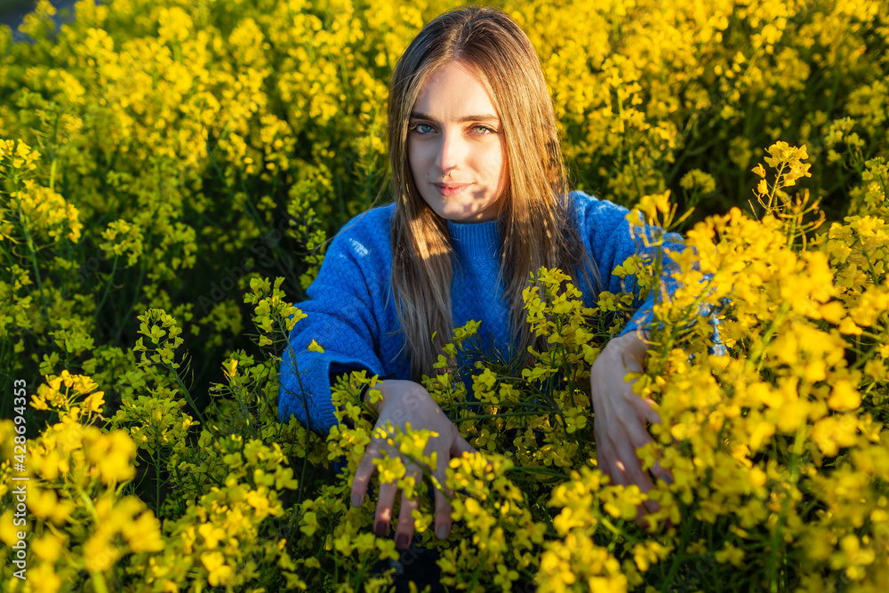 Young blonde girl in a field of rapeseed at sunset Young blonde girl in a field of rapeseed at sunset