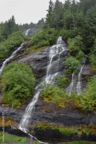 A triple waterfall cascades down a mountainside in the Misty Fjords National Monument in Alaska.