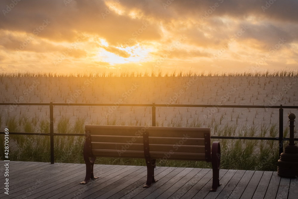 Empty bench sunrise featuring boardwalk, beach, and summer