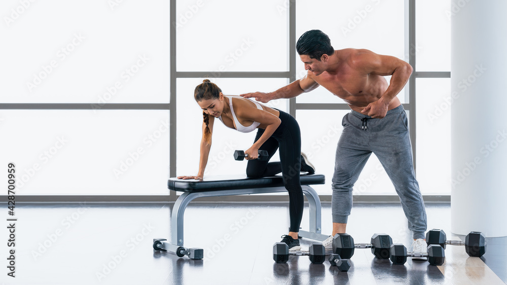 Fototapeta premium gym trainer coaching athletic woman workout with dumbbell lifting