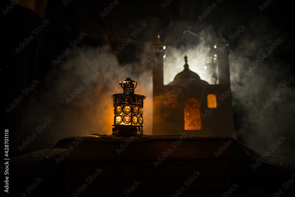 Fototapeta premium Ornamental Arabic lantern with burning candle glowing at night. Festive greeting card, invitation for Muslim holy month Ramadan Kareem.