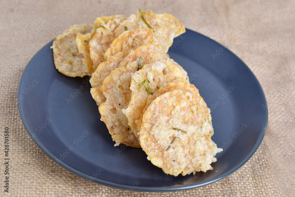 Keripik tempe , tempeh crackers in a black plate. Indonesian traditional snack.Brown texture