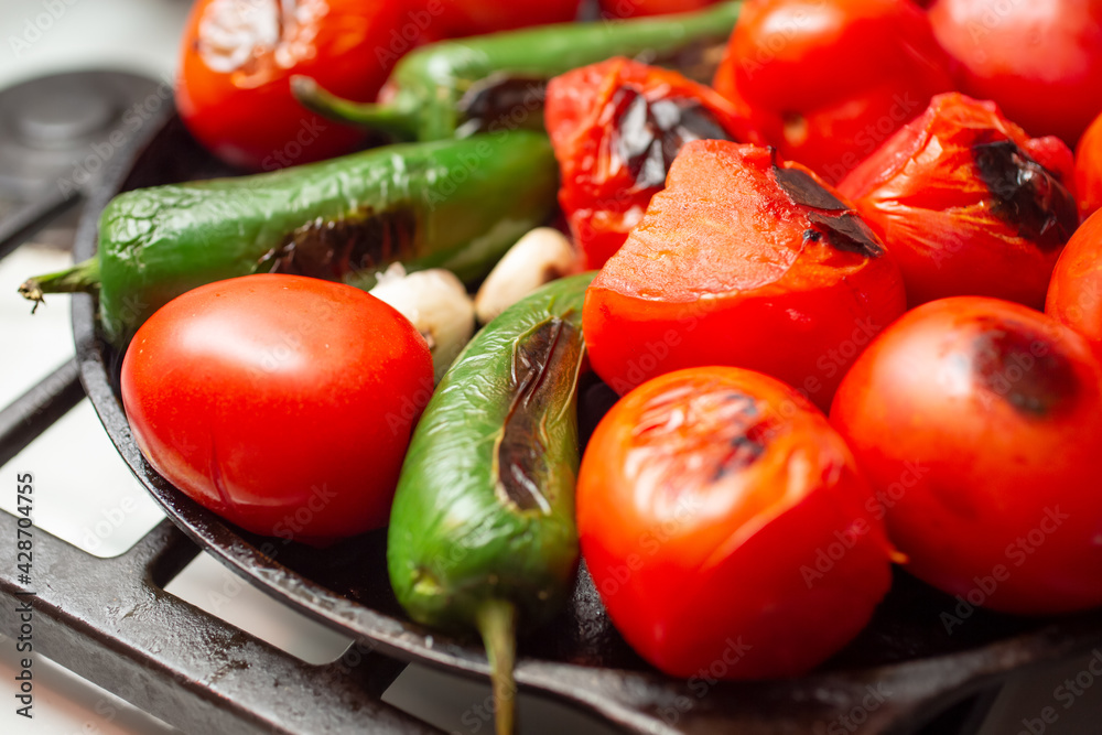 A closeup view of a salsa vegetable ingredients roasting on a comal. A closeup view of a salsa vegetable ingredients roasting on a comal.