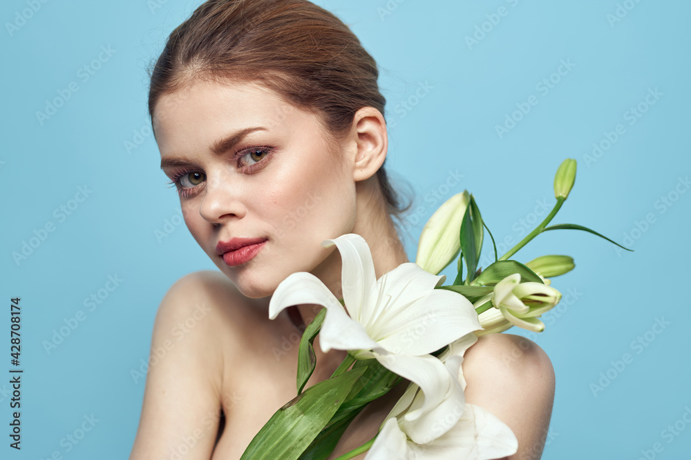 Beautiful girl with a bouquet of white flowers on a blue background cropped view naked shoulders portrait