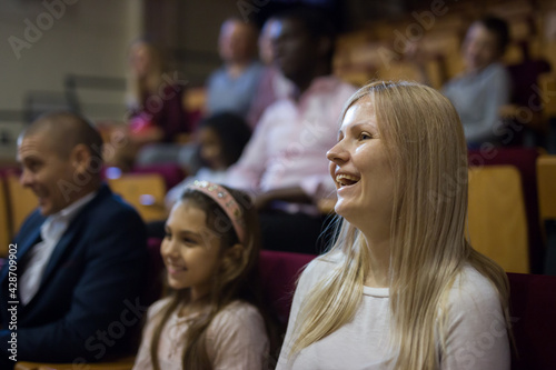 caucasian woman sitting at funny perfomance in theatrical auditorium