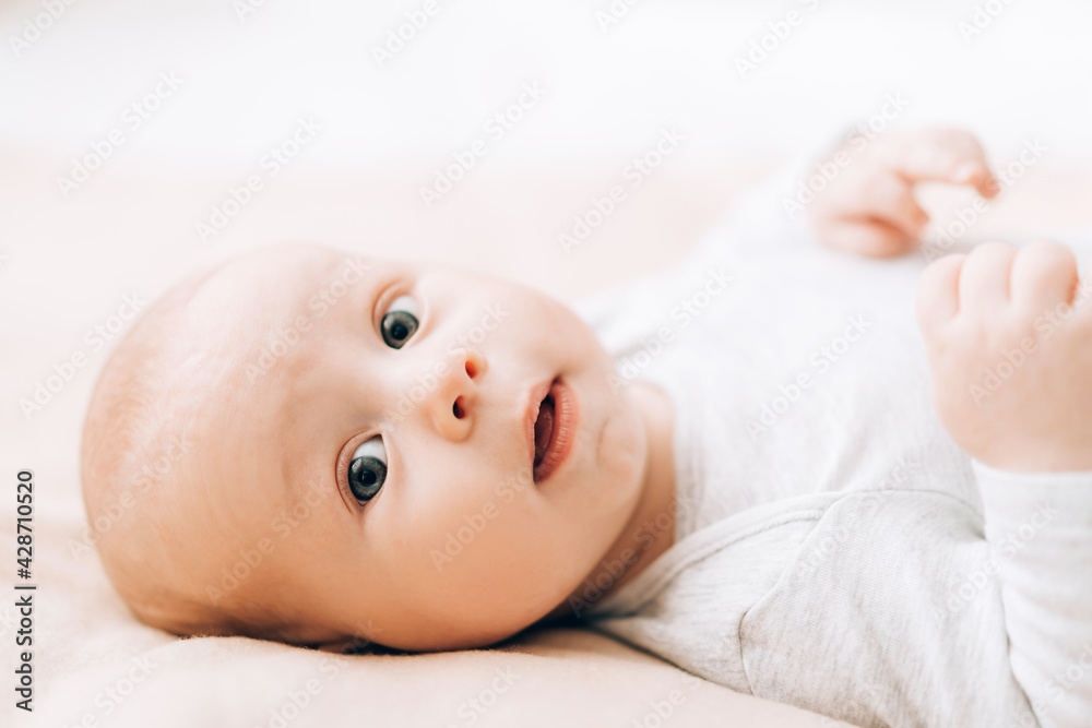 Small child lies on the bed and looks at the camera. Love and care for children. Adoption of children Small child lies on the bed and looks at the camera. Love and care for children. Adoption of children