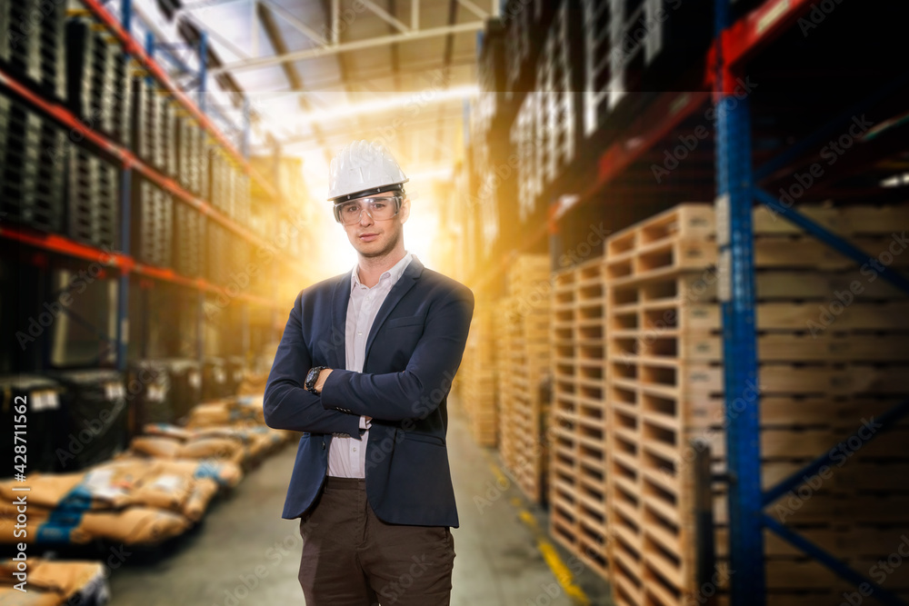 Portrait engineer factory wearing suite and helmet posing  inspection and checking warehouse product factory with industry warehouse background.