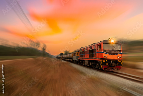 Fast speed motion cargo train on railway with twilight sun sky background.