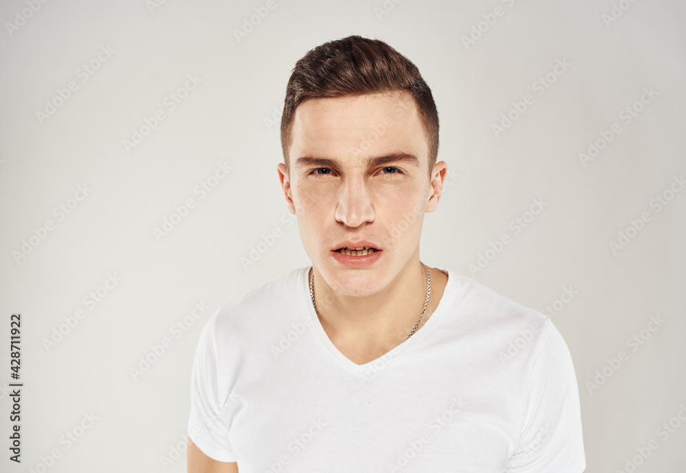 Nice guy in a white T-shirt on a light background cropped view portrait close-up Nice guy in a white T-shirt on a light background cropped view portrait close-up
