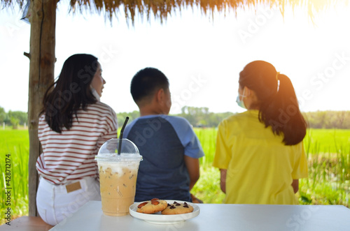 Iced coffee mugs and cookies placed on the table, background, mothers and children sunrise effect.