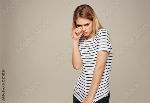 Upset woman emotions blonde beige striped t-shirt background