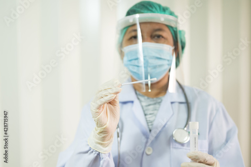 Doctor taking a swab for corona virus sample from potentially infected Asian boy nose.Covid-19 laboratory test.Medical staff with PPE suit test coronavirus covid-19  by nose swab at hospital.