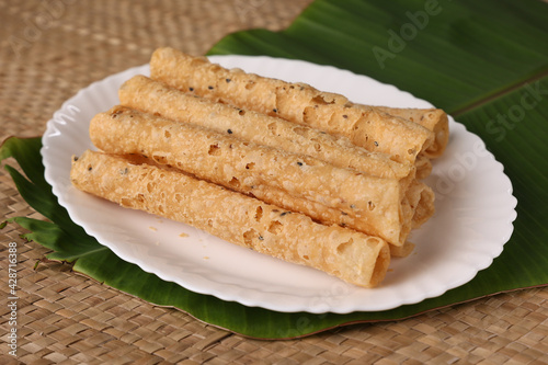 Indian fried snack Kuzhalappam Kerala fried snacks food on banana leaf background. Kerala tea time food fried in coconut oil. Top view of South Indian snacks.	 photo
