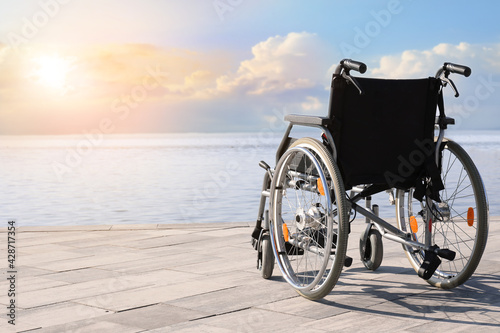 Empty modern wheelchair near river on embankment