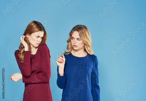 two girlfriends in dress conflict emotions blue background studio