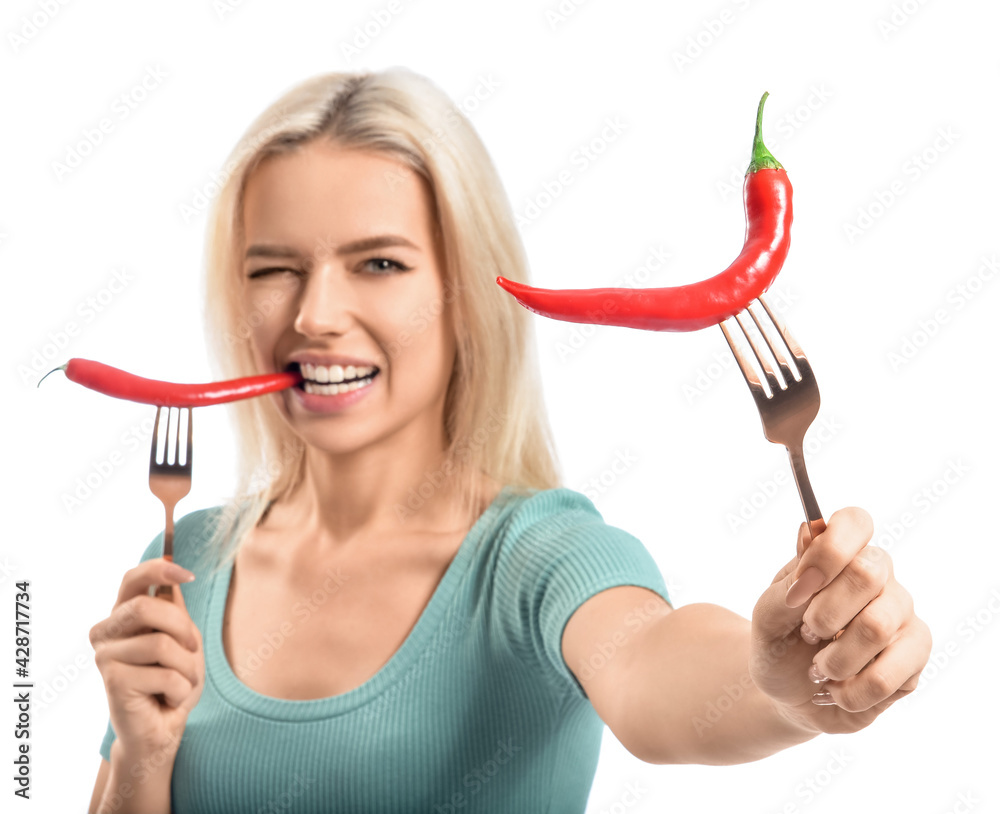 Beautiful young woman eating hot chili peppers on white background Beautiful young woman eating hot chili peppers on white background