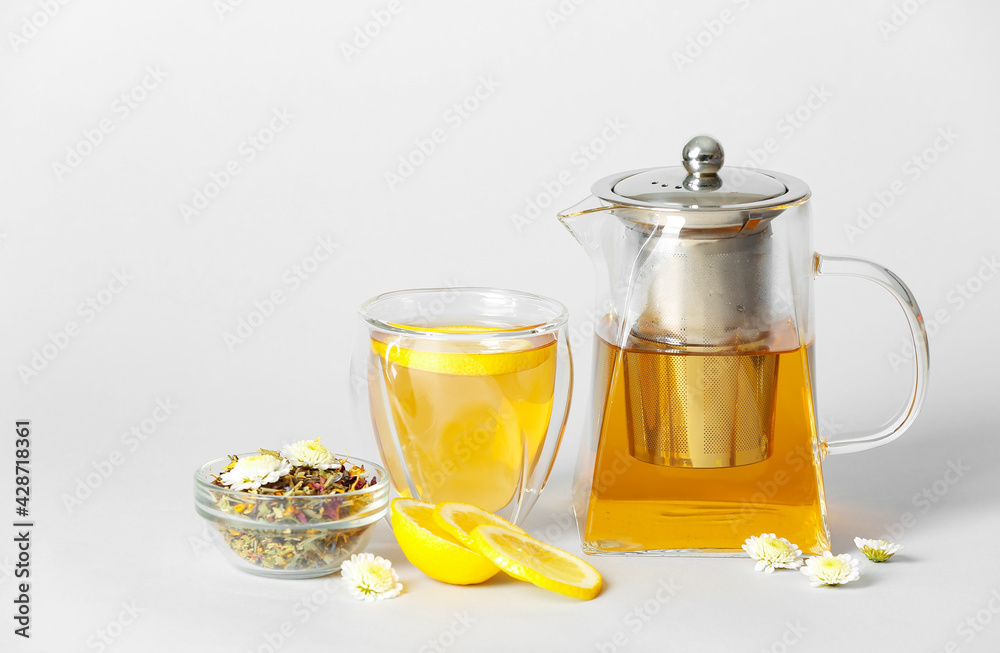 Teapot with hot tea, dry leaves and lemon on light background Teapot with hot tea, dry leaves and lemon on light background