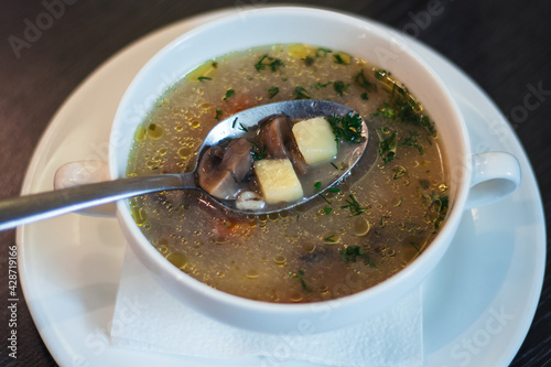 Lean mushroom soup. Spoon with broth, mushrooms and potatoes, in deep white bowl