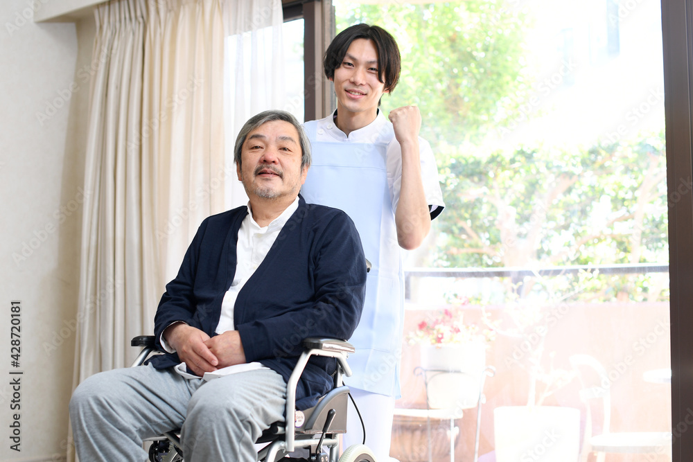 車椅子に乗る高齢者男性とガッツポーズをする男性介護士 車椅子に乗る高齢者男性とガッツポーズをする男性介護士