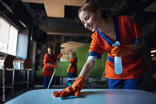 Three female workers using various janitorial supplies during the clean-up photo