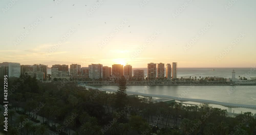 Epic sunrise behind the skyscraper buildings on the harbor of Malaga early in the morning. Beautiful vibes and colorful sky. Wide shot. Epic sunrise behind the skyscraper buildings on the harbor of Malaga early in the morning. Beautiful vibes and colorful sky. Wide shot.