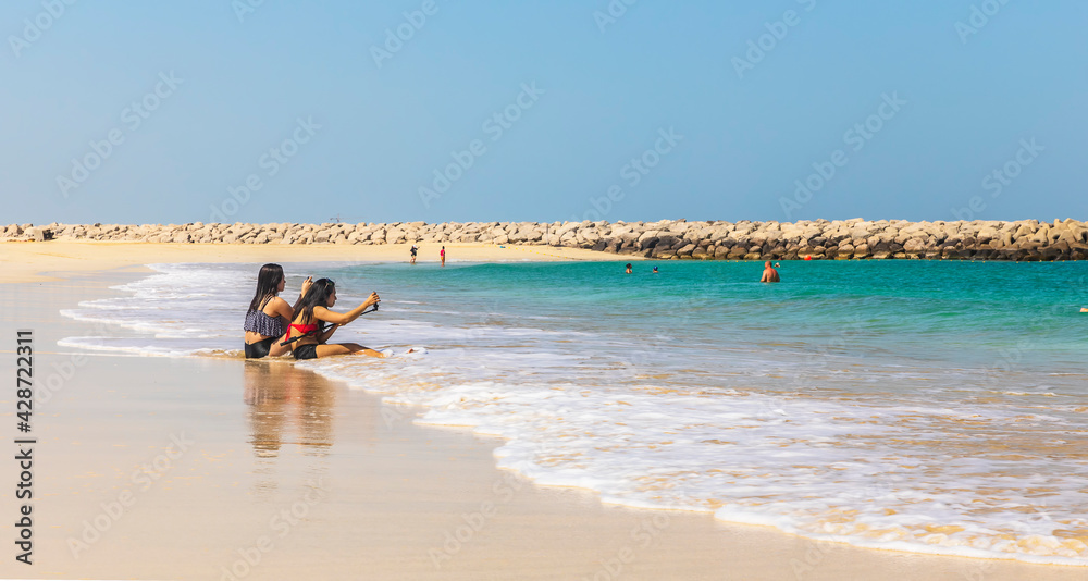 Dubai, UAE - March 04, 2021: Asian girls taking pictures of themselves on the beach Dubai, UAE - March 04, 2021: Asian girls taking pictures of themselves on the beach