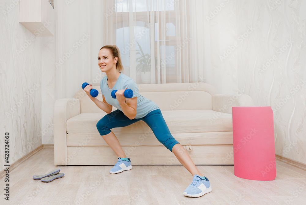 Happy slim attractive woman training with dumbbells at home to keep fit, physical fitness health without a gym Happy slim attractive woman training with dumbbells at home to keep fit, physical fitness health without a gym