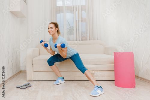 Happy slim attractive woman training with dumbbells at home to keep fit  physical fitness health without a gym