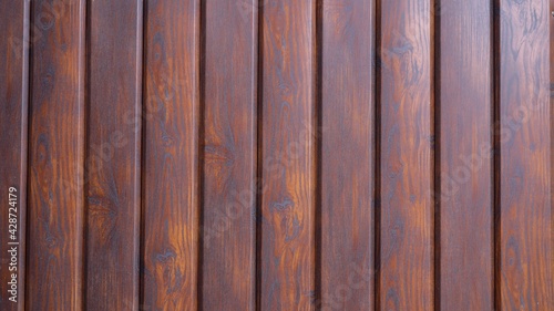 dark brown rustic background from planks of smoothly polished wood treated with stain, country-style backdrop surface in dark colors with a pronounced wood pattern