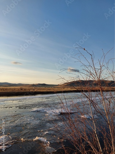 Fototapeta Naklejka Na Ścianę i Meble -  Melting River Ice and Water in Spring Sunset with Mountain on Horizon 