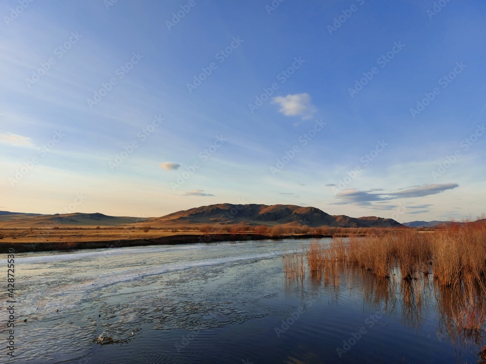 Fototapeta premium Melting River Ice and Water in Spring Sunset with Mountain on Horizon 