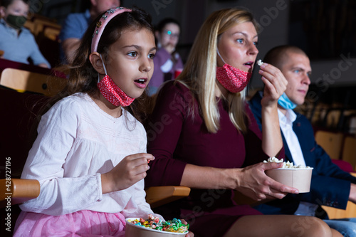 mother, her child sitting at film in auditorium during epidemic