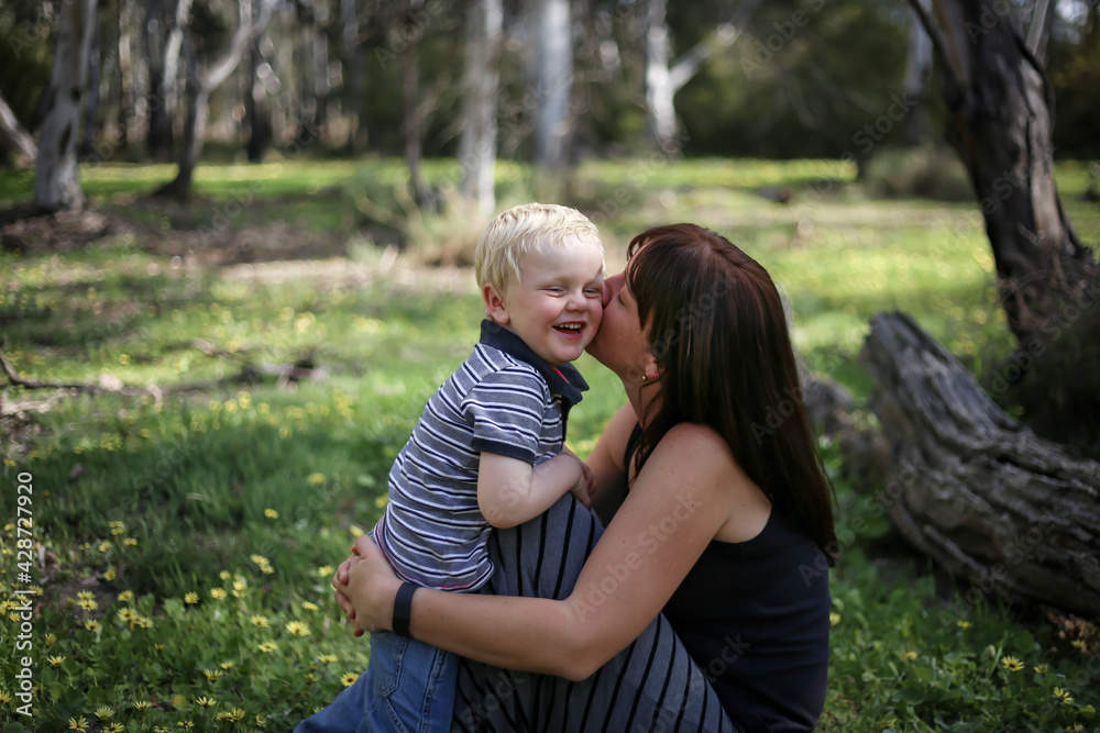 Mother and son snuggling in field full of spring wildflowers Mother and son snuggling in field full of spring wildflowers
