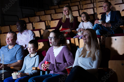 Spectators eating popcorn and watching a movie at the cinema