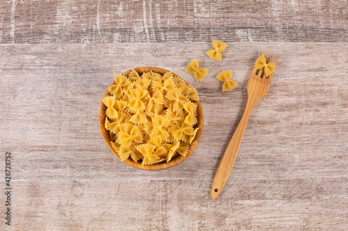 Farfalle pasta in wooden bowl with fork. photo