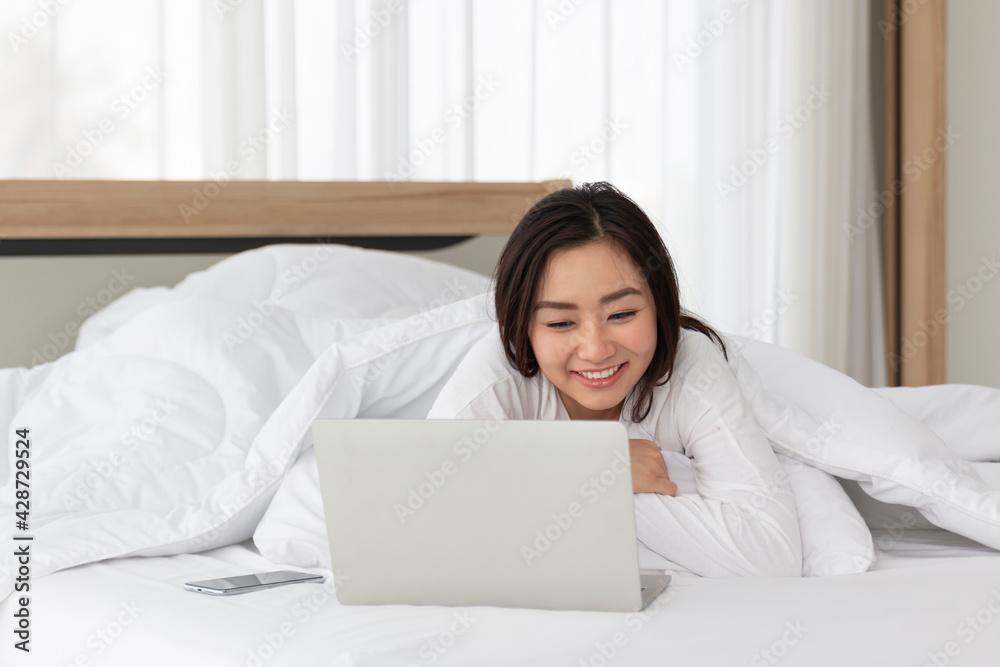 Young female laying on bed using notebook computer. Happy female using laptop at home in bedroom. Working from home in quarantine lockdown. Women watching movie on laptop lying in bed. Young female laying on bed using notebook computer. Happy female using laptop at home in bedroom. Working from home in quarantine lockdown. Women watching movie on laptop lying in bed.