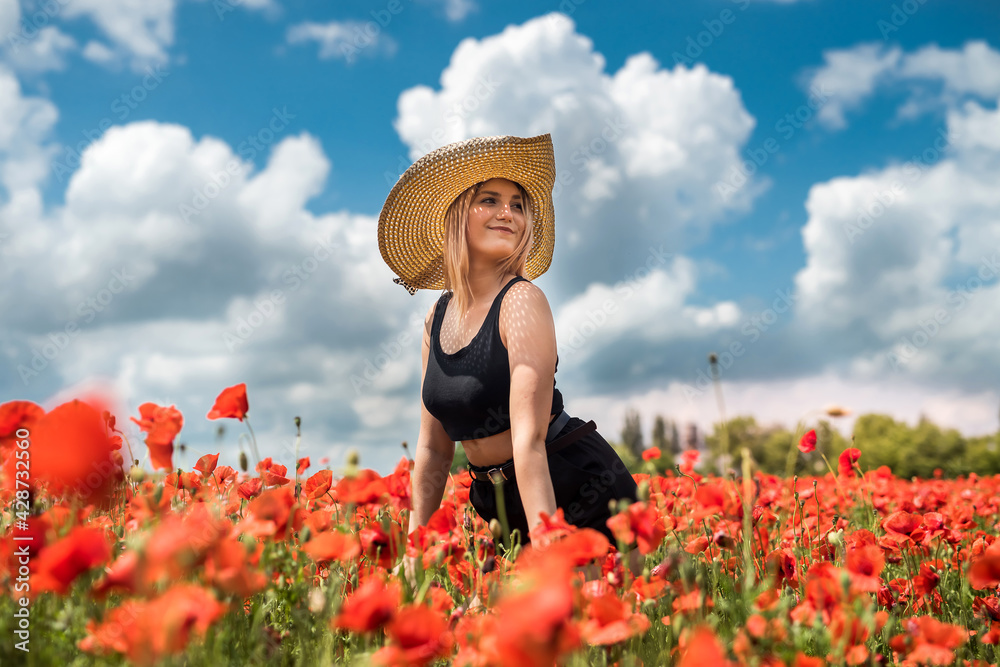 beautiful young  woman in a straw hat in a poppy field at summertime