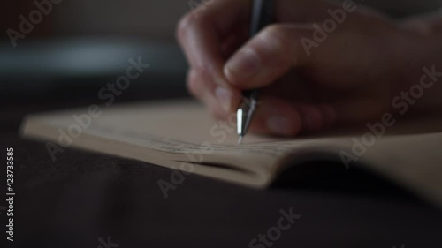 Macro close-up view of female hand making notes, writing letter in vintage sketchbook with brown pages, notebook, diary. Education concept, woman studies. Create to do list. Keep a diary of memories