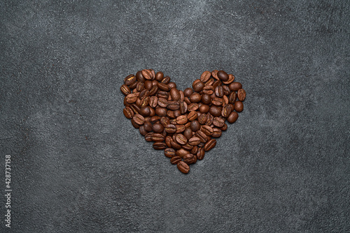 Heart shaped roasted coffee beans on dark concrete background
