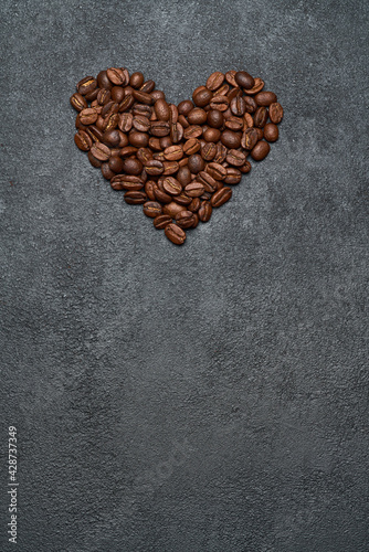 Heart shaped roasted coffee beans on dark concrete background